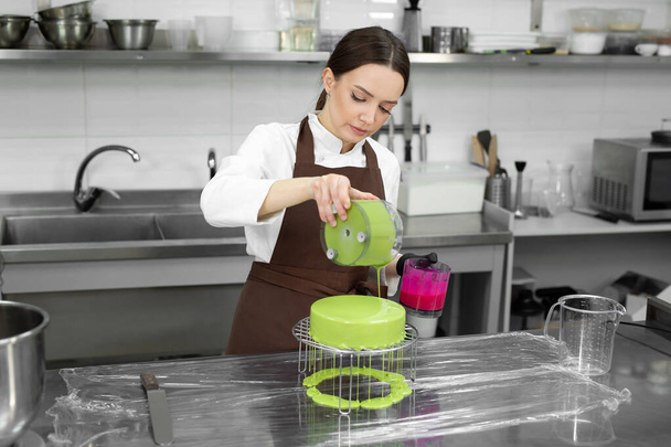 Female pastry chef decorates a mousse cake with a mirror glaze. - Foto, Imagen