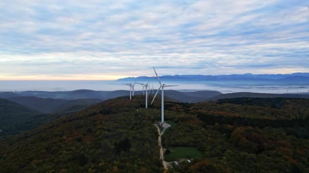 Turbinas eólicas en las montañas durante el amanecer y espesa niebla matutina en el valle. Parque eólico que produce energía verde. - Imágenes, Vídeo