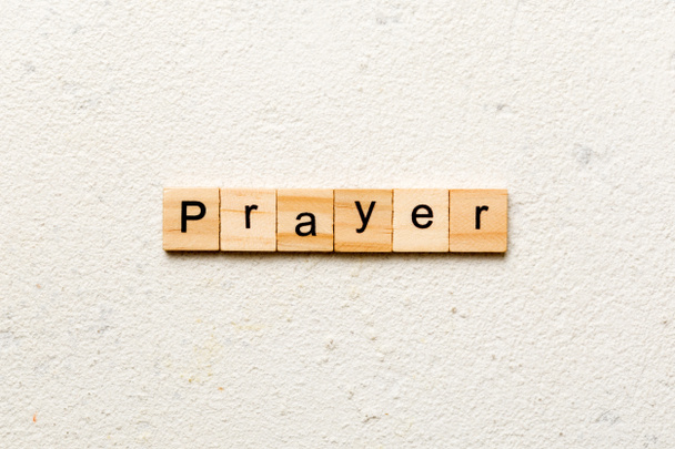 Слово PRAYER написане на дерев'яному блоці. Текст PRAYER на цементному столі для вашого бажання, концепція
. - Фото, зображення