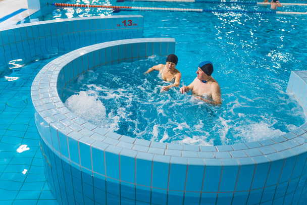 Variété de piscines du parc de la piscine. Couple de retraités caucasiens ou grands-parents passent activement leur temps libre en nageant dans la rivière paresseuse et jacuzzi. Photo de haute qualité - Photo, image