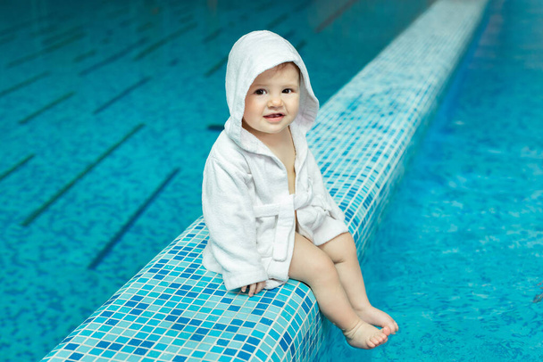 Baby, a small child in a bathrobe towel in the pool. - Photo, Image