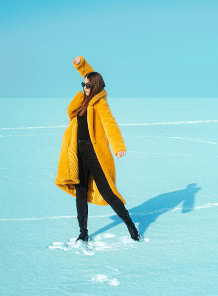 雪氷の上を歩く黄色のコートの若い幸せな女性。、自由の概念 - 写真・画像