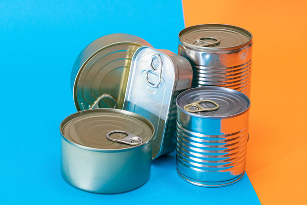 A Group of Stacked Tin Cans with Blank Edges on Split Blue and Orange Background. Canned Food. Different Aluminum Cans for Safe and Long Term Storage of Food. Steel Sealed Food Storage Containers - Foto, Imagem