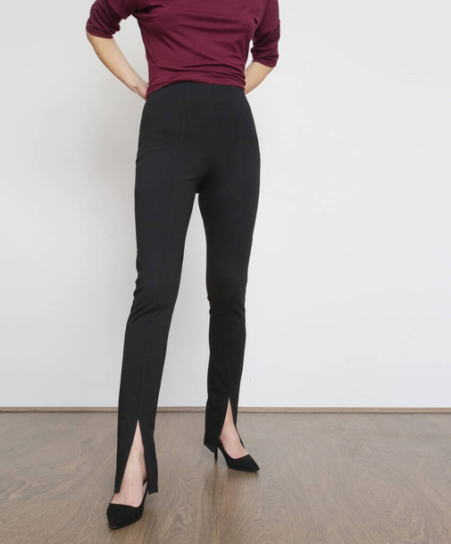 Modèle féminin portant un pantalon skinny décontracté noir avec des fentes. Plan studio. - Photo, image