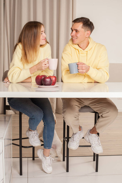 Fröhliches Kirmespaar in der Küche sitzt am Tisch und trinkt aus den Tassen - Foto, Bild