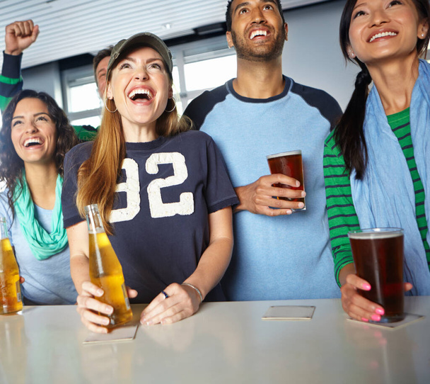 Come on. A group of friends cheering on their favourite sports team at the bar - 写真・画像