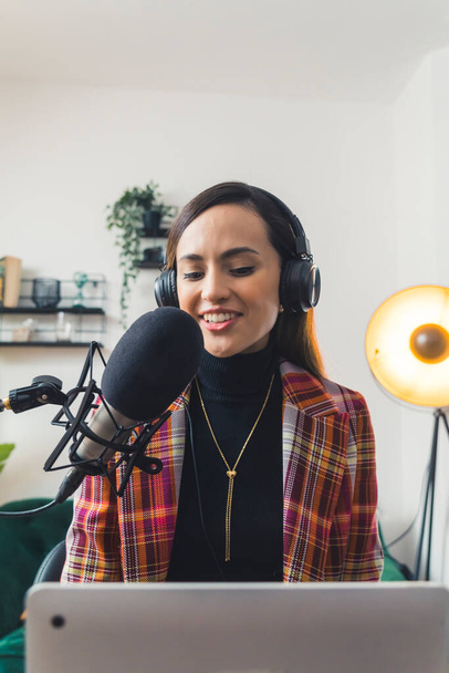 vertical shot of a smiling girl with headphones talking to her guest into a microphone, medium shot. High quality photo - Photo, image
