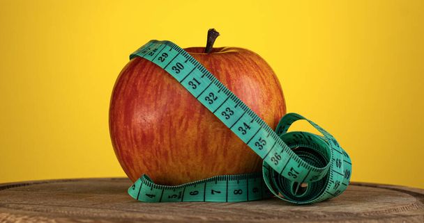 Il nastro di misura è avvolto intorno alla mela. Il concetto di nutrizione sportiva, fitness e dieta. - Foto, immagini