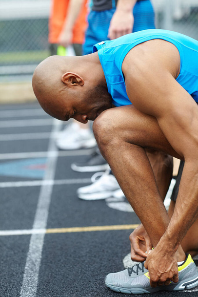 Koşmak için güzelce ve sıkıca kavrıyorum. Yarışa hazırlanmak için ayakkabı bağcıklarını bağlayan bir erkek sporcunun yan görüntüsü - Fotoğraf, Görsel
