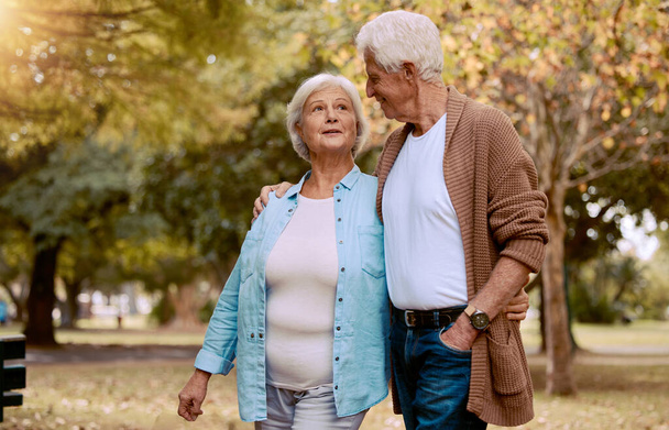 Senior couple, bonding or walking in nature park, city garden or public environment in relax exercise, mobility or retirement break. Smile, happy woman or talking elderly man in hug and weekend date. - Foto, Imagem