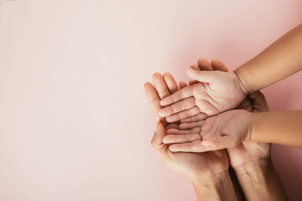 Close up hands children on adult mother hand, Top view person kid stack mom palms, Parents and little kid holding empty hands together isolated on pink background, Family day care concept - Foto, imagen