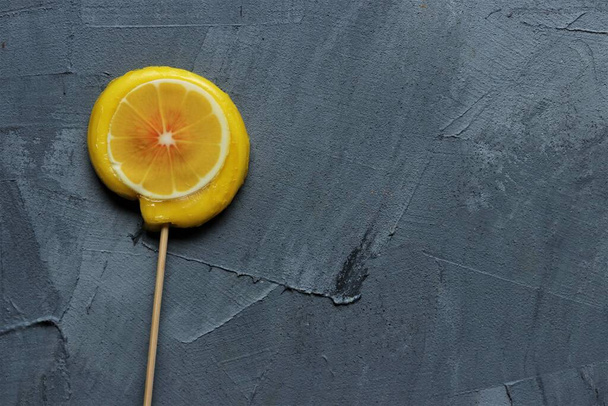 Orange and lemon lollipops on a grey background - Foto, imagen