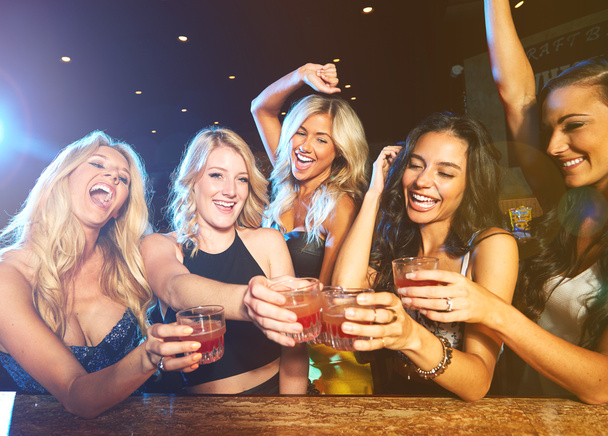 Barátaim, buli a nightclubban koktéllal és pirítóssal, szórakozás és boldogság a nőkkel az újévi ünnepségen. Éjszaka, izgatott az alkohol koktélok és éljenzés az energia, tánc és italok - Fotó, kép