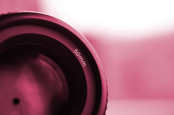 Egy portréobjektív töredéke egy modern SLR fényképezőgéphez. Fénykép egy széles apertúrájú objektívről, melynek fókusztávolsága 50mm Viva Magenta, színe 2023 év - Fotó, kép