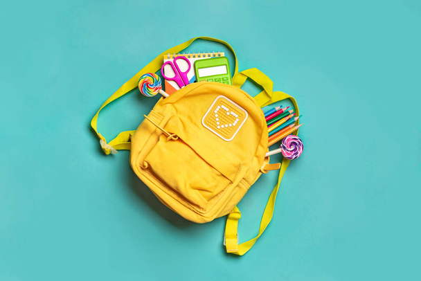 Вернуться в школу, концепция образования Желтый рюкзак со школьными принадлежностями - ноутбук, ручки, ластик радуга, номера изолированы на синем фоне. - Фото, изображение