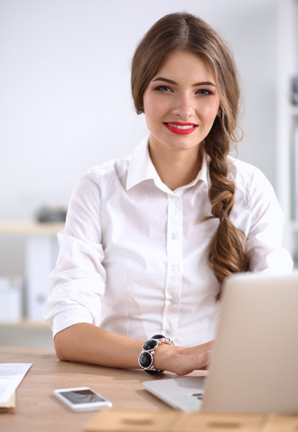 Attractive businesswoman sitting  on desk in the office - Photo, image