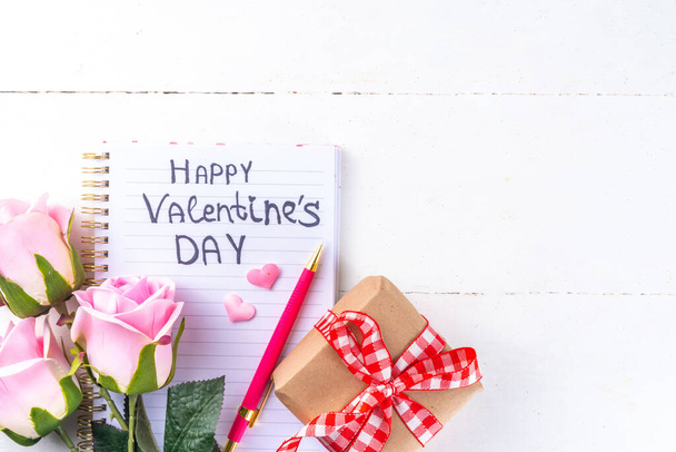 8 marca Dzień Kobiet, Walentynki kartka okolicznościowa tło z bukietem kwiatów róż, pudełko prezentów z czerwoną wstążką, kształty serca wystrój, na białym drewnianym stole widok góry przestrzeń kopia  - Zdjęcie, obraz
