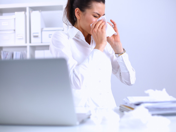 Young businesswoman blowing her nose, sits at the desk - Fotoğraf, Görsel