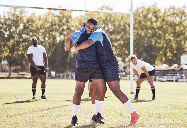 Dos compañeros de equipo de rugby afroamericanos celebran anotar un intento o ganar un partido afuera en un campo de deportes. Jugadores de rugby vitoreando durante un partido después de anotar. Trabajo en equipo asegura el éxito y la victoria. - Foto, Imagen