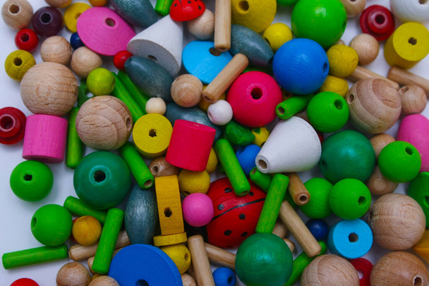 Colorful wooden seed beads of different sizes, background. Making eco friendly wooden colourful baby beads. Hobby, crafting, creativity, free time at home concept. Making of handmade jewellery - Photo, Image