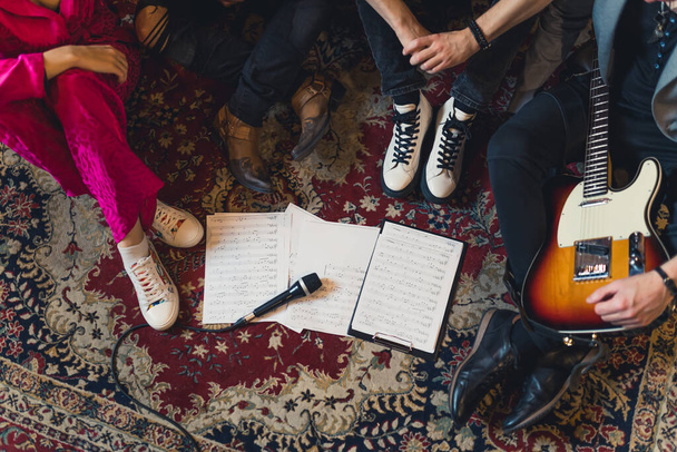 Fascia musicale seduta insieme sul pavimento con note. Senza volto Foto di alta qualità - Foto, immagini