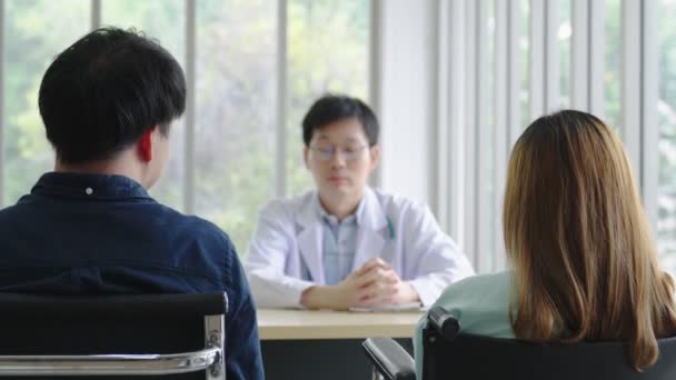 Улыбающийся азиатский педиатр-мужчина дает советы пациентам, молодой врач-азиат консультирует пациентку и проводит обследование в больнице, лечение и концепцию помощи - Кадры, видео