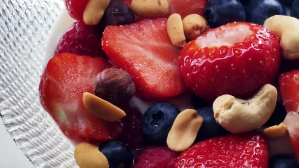 Terveellinen aamiainen ja luomuruoka, mansikat, vadelmat, mustikat ja maapähkinät laktoosittomalla jogurtilla kulhossa, ruokavalio ja ravitsemus, maukas resepti-idea. Laadukas 4k kuvamateriaalia - Materiaali, video