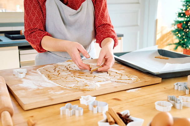 Naisen kädet laittaa keksejä muoto joulun piparkakkuja uunissa paperille. Leipoa kotitekoisia leivonnaisia. Joulu ja uudenvuoden perinteet juhla ruoka. - Valokuva, kuva