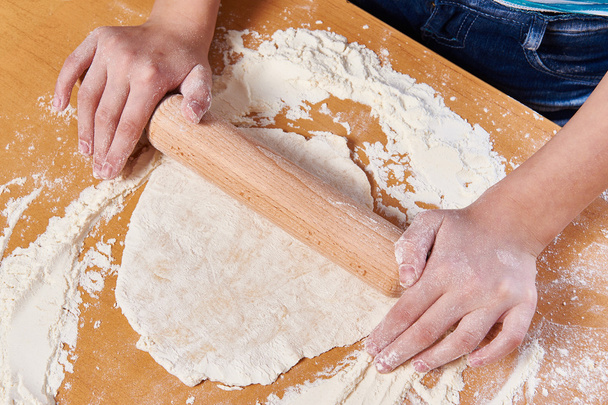 Girl prepare dough with rolling pin on kitchen table - Foto, Imagen