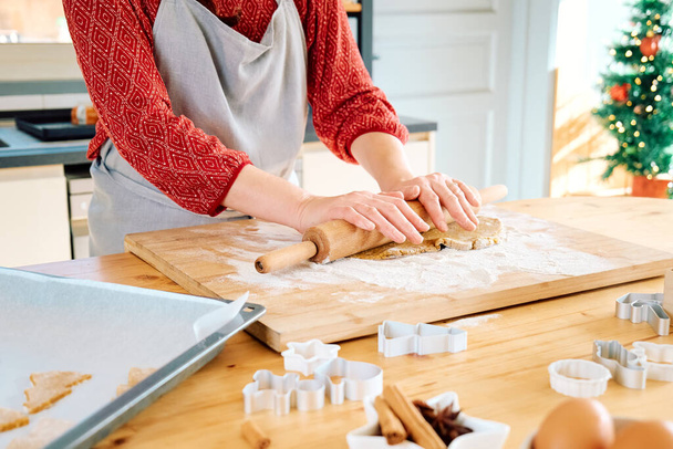 Naisen kädet litistävät taikinaa rullalla joulun piparkakkuja varten, leivonnaisia leipomalla kotitekoisia leivonnaisia online-reseptistä. Joulu ja uudenvuoden perinteet juhla ruoka. - Valokuva, kuva