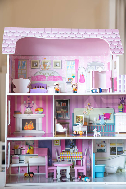 La foto de la enorme modelo de casa de muñecas rosa amueblada con muebles en miniatura en una habitación para niños.   - Foto, imagen