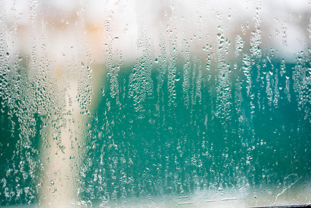 Капельки конденсации на пластиковом оконном стекле от изменения температуры.  - Фото, изображение
