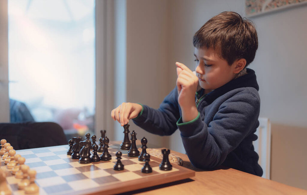 Concentrated Young boy developing chess strategy, playing chessboard game with friend or family at home. Activity or Hobby for Family Concept  - Φωτογραφία, εικόνα