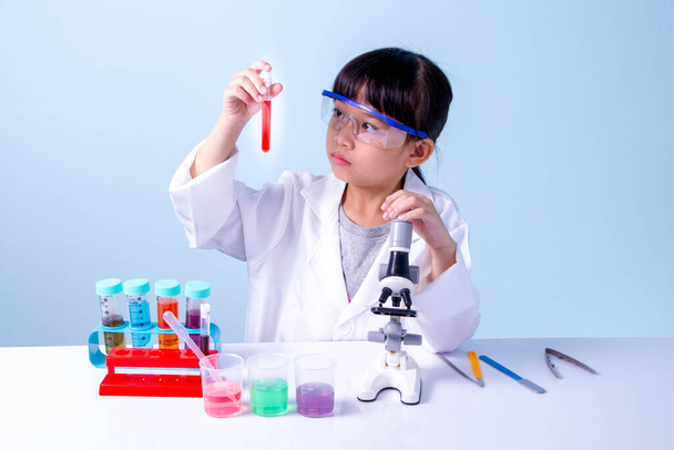 Malá asijská roztomilá dívka 7 let roli hraje vědec ve vědecké laboratoři s vybavením a při pohledu na kapalné chemikálie v trubkách. - Fotografie, Obrázek