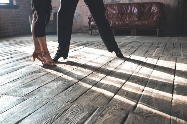 Δύο πόδια από δύο επαγγελματίες χορευτές χορού χορεύουν στο στούντιο της σοφίτας. Όμορφη καλλιτεχνική παράσταση με βαρύ καπνό. Αθλητική ζωή έννοια. Πάθος και συναισθηματικός χορός. - Φωτογραφία, εικόνα