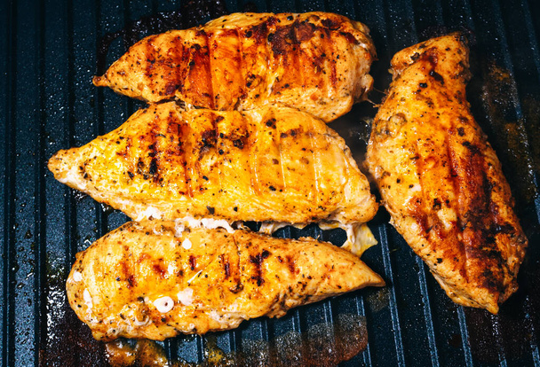 Delicious juicy chicken steak seasoned with herbs and spices is fried in a grill. Barbecue party. - 写真・画像