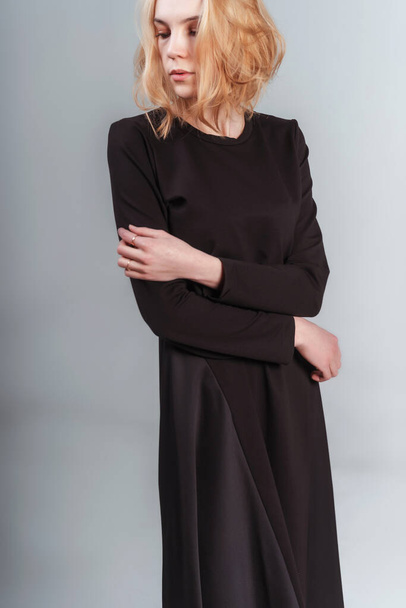 portrait of a Russian girl in a black dress on a white background. photo session of black clothes on a light background. blonde girl in black cotton dress - Fotografie, Obrázek
