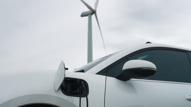 Progresivní koncepce budoucí energetické infrastruktury elektrického vozidla nabíjeného na nabíjecí stanici poháněné zelenou a obnovitelnou energií z větrné turbíny s cílem chránit životní prostředí. - Záběry, video