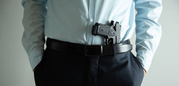 man hand holding gun on grey background - Foto, imagen
