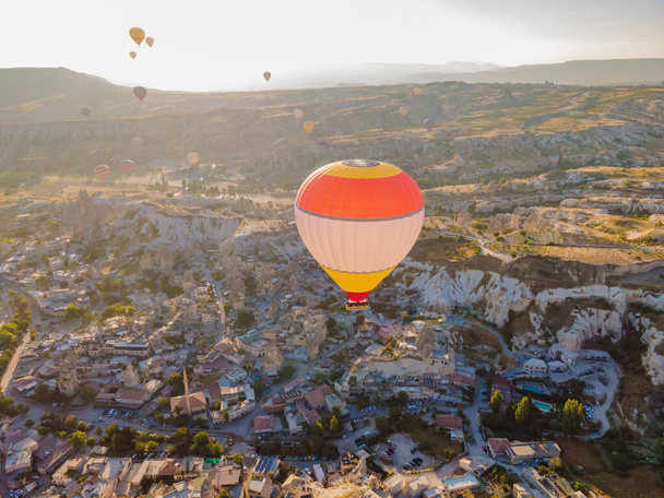 Colorful hot air balloons flying over at fairy chimneys valley in Nevsehir, Goreme, Cappadocia Turkey. Spectacular panoramic drone view of the underground city and ballooning tourism. High quality. - Fotografie, Obrázek