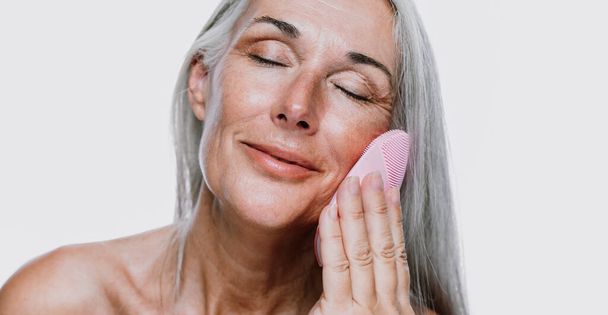 Image of a beautiful senior woman posing on a beauty photo session. Middle aged woman on a colored background. Concept about body positivity, self esteem and body acceptance - Фото, зображення