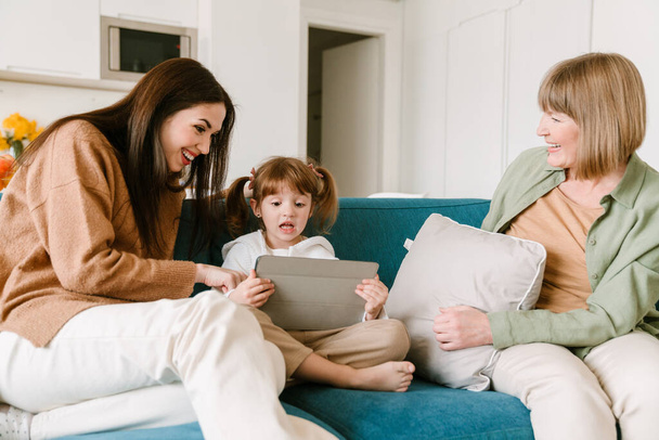 White girl using tablet computer while spending time with her family at home - Foto, afbeelding