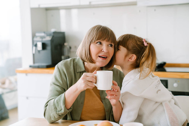 White blonde girl having breakfast with her grandmother at home - Valokuva, kuva
