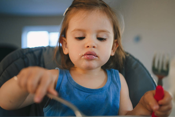 Menina da criança comendo mingau de cereal sentado na mesa em uma cadeira alta das crianças. Primeiro alimento para bebés, puré. - Foto, Imagem