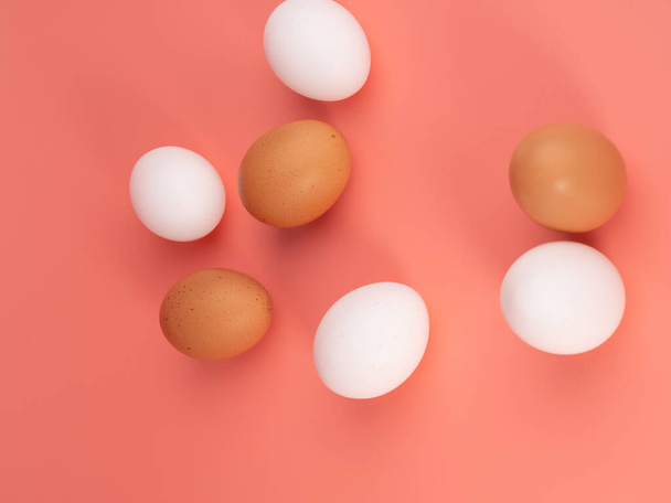 Kippeneieren op een roze achtergrond. Wit en bruin ei op een roze achtergrond. Close-up. - Foto, afbeelding
