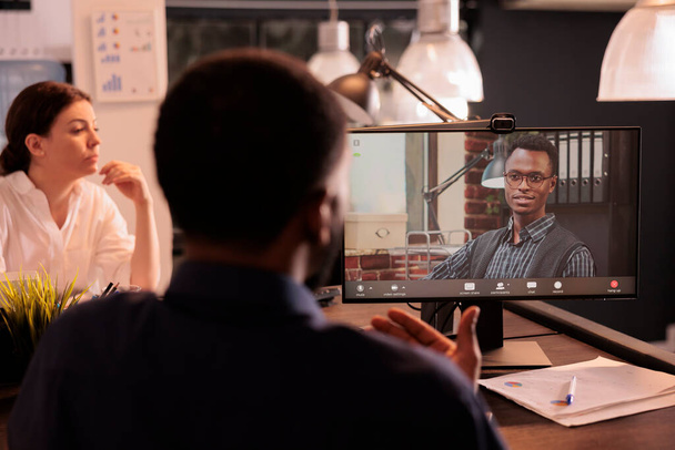 アフリカ系アメリカ人のエグゼクティブマネージャーが企業のビデオコールについて話し合い、ウェブカメラのテレビ会議のスタートアップ戦略について話し合います。ビデオ会議で従業員の話を聞く会社のチームリーダー - 写真・画像