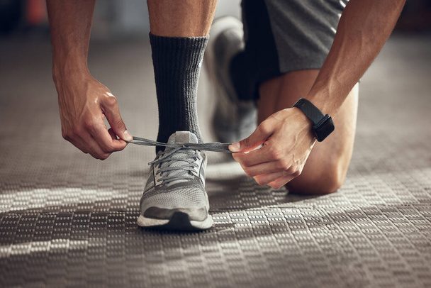 Closeup on feet of athlete tying shoe laces. Hands of bodybuilder getting ready to workout. Closeup on hands of fit man tying sport shoe laces. Athlete ready for a workout cropped. - Photo, Image