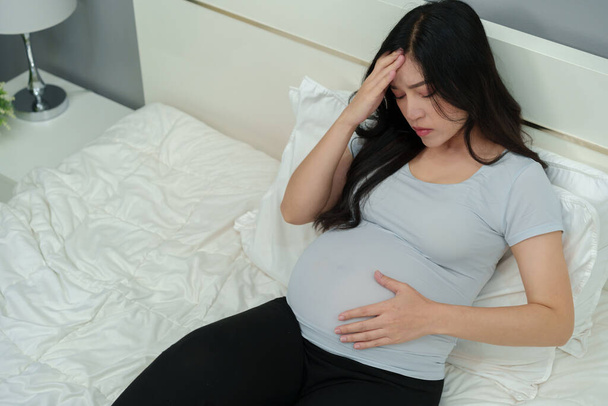 stressed pregnant woman suffering headache lying in a bed - Foto, imagen