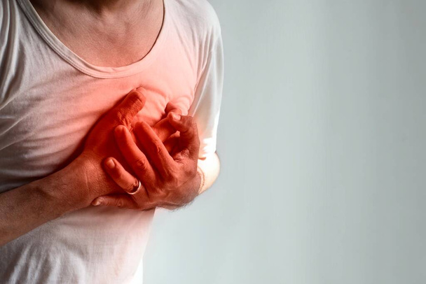 Jovem asiático sofrendo de dor no peito do lado esquerdo. A dor torácica pode ser causada por ataque cardíaco, infarto do miocárdio ou isquemia, miocardite, pneumonia, estresse, etc.. - Foto, Imagem