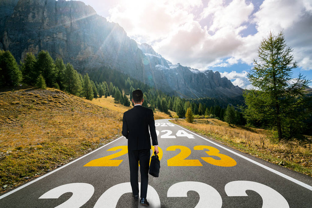 The 2023 New Year journey and future vision concept . Businessman traveling on highway road leading forward to happy new year celebration in beginning of 2021 for fresh and successful start . - Photo, Image